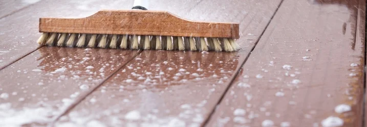 Schrubben einer Holzterrasse mit Bürste